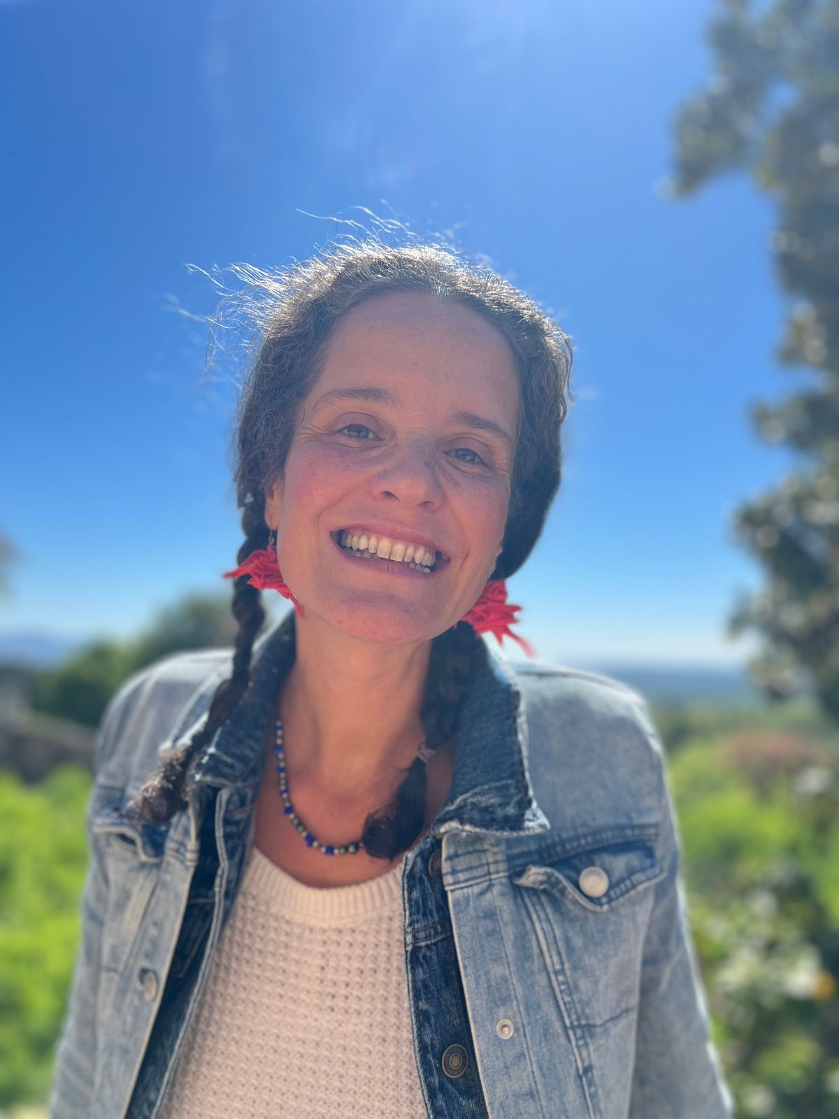 Retrato de María Nora sonriendo, con trenzas y flores rojas