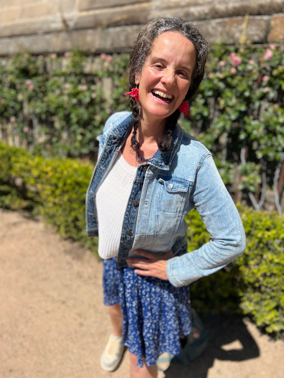 María Nora riendo, con chaqueta vaquera y flores rojas en el pelo